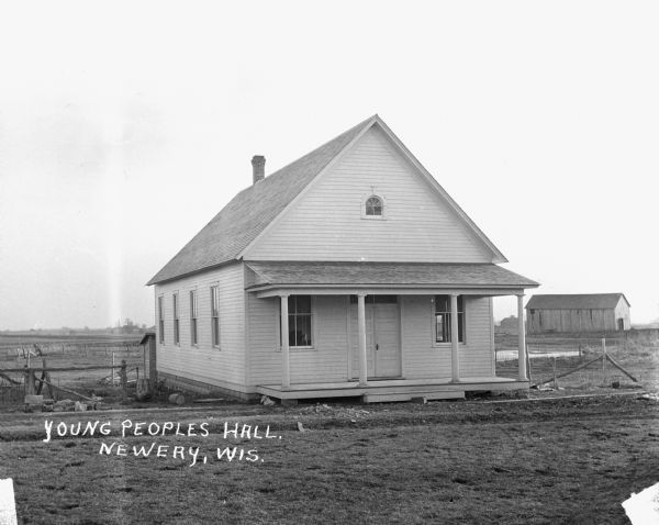 Exterior of the Young People's Hall building. There are fields and a barn in the background.
