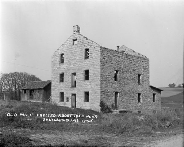 Ruins of the Old Mill, a stone building which has no roof and is missing window glass. Behind on the left is an abandoned shed.