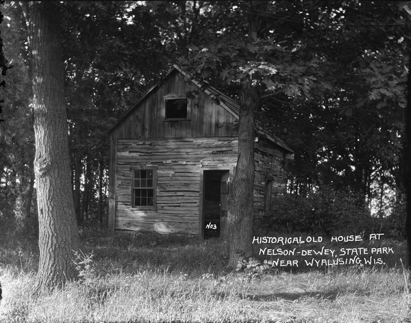 An old log house in the woods at Nelson Dewey State Park surrounded by oak trees.