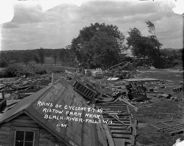 Ruins after a tornado. Demolished farm buildings, wagons and a windmill.