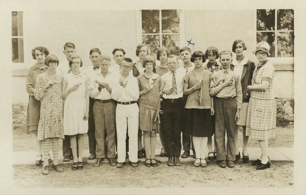 Photographic postcard of outdoor group portrait of the 7th and 8th grade harmonica (mouth organ) class. Sherwin Gillett's son Lorin is identified with an "X" in the top row.