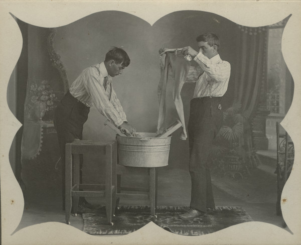 Trick photograph featuring two images of Sherwin Gillett doing laundry in a washtub. He is posing in front of a painted backdrop.