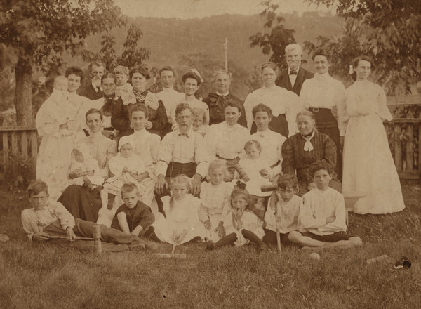 Outdoor group portrait of the 25th wedding anniversary of Bradford and Alice Gillett — Sherwin Gillett's uncle and aunt, seated in the center. The other guests are unidentified. The children in the front row have croquet mallets.