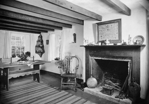 View of a room in Pendarvis House. There is a map of Cornwall over the fireplace. A bedwarmer and a bellows sit at the base of the hearth.