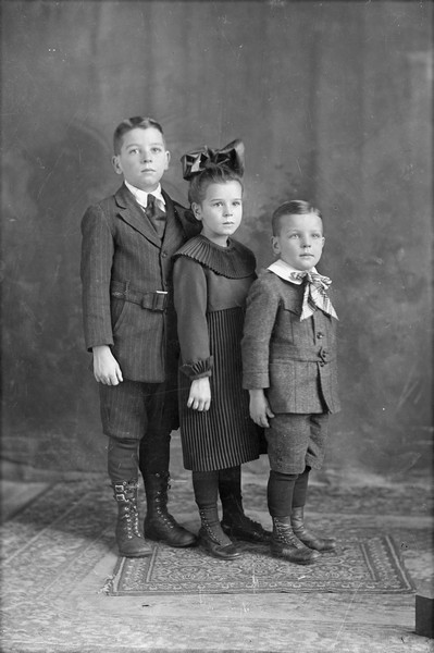 Studio group portrait in front of a painted backdrop of the Gillett children, left to right: Harry (b. 1910), Sherry (b. 1913), and Lorin (b. 1915).