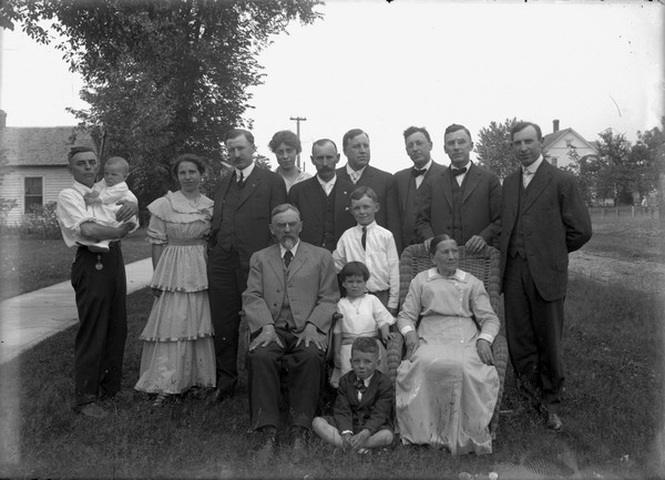 Outdoor group portrait of the Conrad Schmitt family. Sherwin and Emma (nee Schmitt) Gillett are standing on the far left. Sherwin is holding infant son, Lorin. Conrad and Maria Schmitt are seated. The other Schmitt children are standing. In birth order they are: Charles (b. 1868), Alfred (b. 1870), Louis (b. 1873), Christoph (b. 1876), Otto (b. 1879), Herbert (b. 1882), Emma (b. 1884) and Elena (b. 1887). The children are unidentified, but Harry and Sherry Gillett are probably two of them.