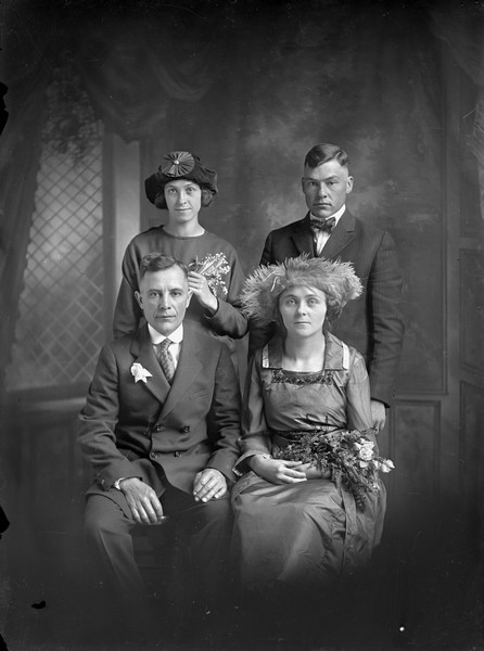 Studio group portrait of four unidentified members of a wedding party. A man and woman sit in front of a man and woman standing.