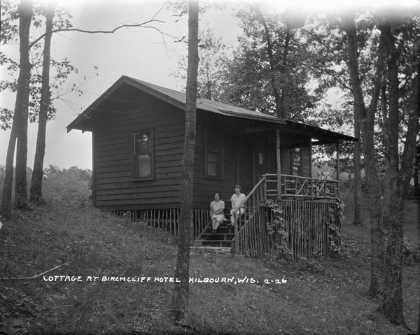 Guest cottage at the Birchcliff Hotel. Two women are seated on the steps to the entrance.