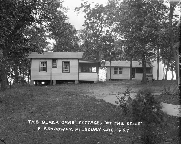Two small wood-frame cottages behind the main building at Black Oaks. A section of the porch of the main building is on the far right.