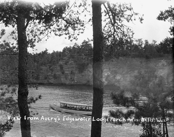 View from the porch of Edgewater Lodge of the Wisconsin River and rock formations. A tour boat with passengers is passing by.