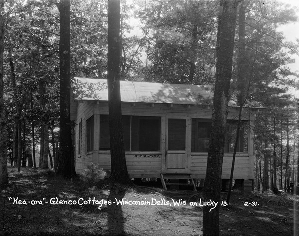 Exterior view of "Kea Ora," a small cottage with a screened-in porch amongst the oaks and pines.
