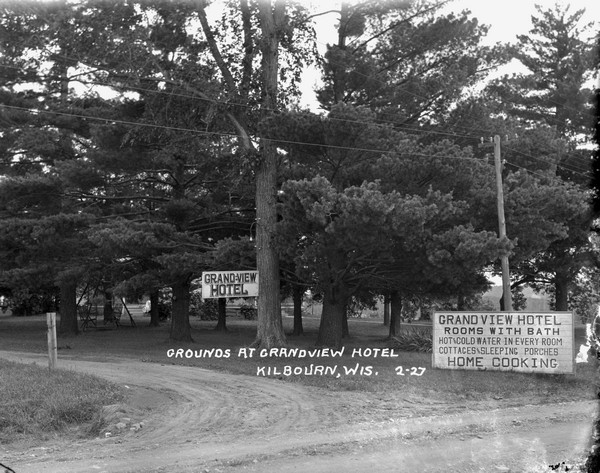 View of the entrance drive of the Grandview Hotel. There is a large signboard advertising the amenities; rooms with baths, hot and cold water, cottages and sleeping porches.
