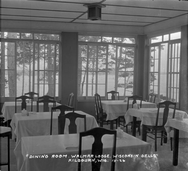 The dining room at the lodge with a view of the Wisconsin River. The tables are set with white tablecloths, sugar bowls and salt and pepper shakers.