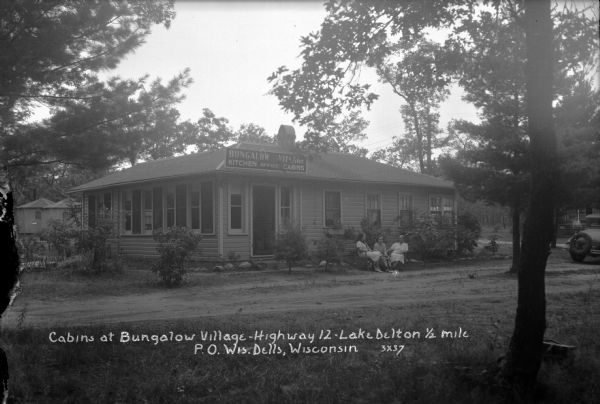 Three women are sitting on chairs in front of the office and kitchen building at Bungalow Village.