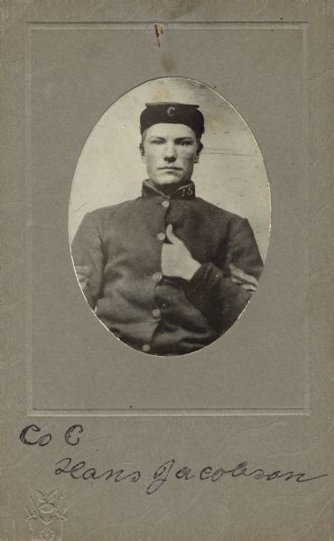 Quarter-length oval studio portrait of Hans Jacobson, a private of Company C, 15th Wisconsin Infantry in uniform and kepi [forage cap] displaying a “C” on the underside of the brim and “15” on the collar of the uniform. The following information was obtained from the Regimental and Descriptive Rolls, Volume 20: He resided in Norway, Wisconsin. On March 14, 1862, he enlisted at Waterford and was mustered into service at Madison, Wisconsin on December 2, 1861, at the age of 25. He was captured during the battle at Stone River, Tennessee and returned to Company C as a paroled prisoner of war. He was held as a paroled prisoner of war at St. Louis, Missouri from March to May 1863. In July 1863, was moved Columbus, Ohio as a paroled prisoner of war until September 25, 1863, when he became ill and was sent to Annapolis, Maryland. He did not muster out with Company C at the term of service.