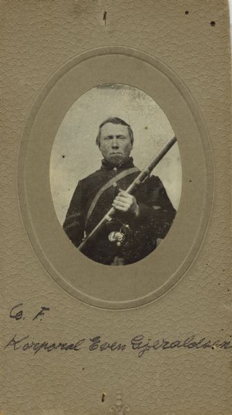 Waist-up oval studio portrait of Even Gjeraldsen, a corporal in Company F, 15th Wisconsin Infantry, in uniform holding his musket across his chest. The following information was obtained from the Regimental and Descriptive Rolls, Volume 20: He resided in Manitowoc, Wisconsin. On October 21, 1861, he enlisted in Manitowoc, Wisconsin and was mustered into service in Madison, Wisconsin on December 12, 1861 at the age of 40. He was appointed corporal on January 1, 1862. He was discharged on November 5, 1863, in Nashville, Tennessee for disability.