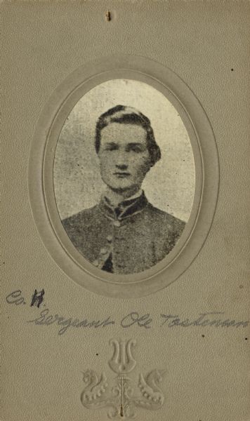Head and shoulders oval studio portrait of Ole Totenson [as written on the photograph backing; also written as Ole Tortenson on Descriptive Rolls, Volume 20 (“Blue Books”); also as Ole Tortstenson on published rosters: Rosters of Wisconsin Volunteers, Volume 1 (1886) and Wisconsin Volunteers (1914), a sergeant in Company H, Wisconsin 15th Infantry,  in uniform. The following information was obtained from the Regimental and Descriptive Rolls, Volume 20: He resided in Christiana, Wisconsin. On December 15, 1861, he enlisted and was mustered into service on February 12, 1862, in Madison, Wisconsin at the age of 18.  On February 16, 1862, he was appointed as a corporal and on August 1, 1862 he was promoted to sergeant. He was mustered out of service on February 12, 1865, in Madison, Wisconsin.