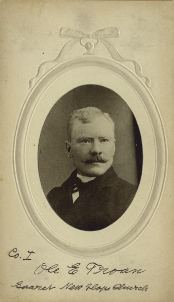 Quarter-length oval studio portrait of Ole E. Troan [as written on the photograph backing, Descriptive Rolls, Volume 20 ("Blue Books") and published rosters: Wisconsin Volunteers: War of the Rebellion (1914) and Rosters of Wisconsin Volunteers, Volume 1 (1886); also as  Ole E. Trean Descriptive Rolls, Volume 20 ("Red Books")], a private in Company I, 15th Wisconsin Infantry. The following information was obtained from the Regimental and Descriptive Rolls, Volume 20: He resided in Madison, Wisconsin. On September 27, 1861, he enlisted in Madison, Wisconsin and on November 16, 1861 he was mustered into service in Madison, Wisconsin at the age of 17. From October to December 1863 he was detached to the 6th Ohio Battery.  During the battle at New Hope Church, Georgia, he was severely wounded in the leg (fractured by shell). He was discharged on December 8, 1864, from Harvey Hospital in Madison, Wisconsin.