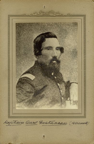 Quarter-length studio portrait of Carl Gustavson [as written on the photograph backing; also written and known as Charles Gustaveson on Descriptive Rolls, Volume 20, published rosters: Wisconsin Volunteers (1914) and Rosters of Wisconsin Volunteers, Volume 1 (1886)], a captain in Company F, 15th Wisconsin Infantry, in uniform. The following information was obtained from the Regimental and Descriptive Rolls, Volume 20: He resided in Eaton, Wisconsin.  On October 21, 1861, he enlisted in Manitowoc, Wisconsin and on December 25, 1861, he was commissioned a captain at the age of 38.  He was wounded during the battle at Stone River, Tennessee on December 31, 1862. In September is captured at Chickamauga, Georgia and held at a prisoner of war camp in Richmond, Virginia until he escaped and came into Union lines at Atlanta, Georgia on September 1864. He was mustered out on January 14, 1865 since the term of service expired.