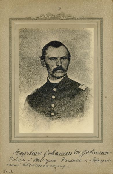 Quarter-length studio portrait of Johannes M. Johnson [as written on the photograph backing; also written and known as John M. Johnson on Descriptive Rolls, Volume 20, published rosters: Wisconsin Volunteers (1914) and Rosters of Wisconsin Volunteers, Volume 1 (1886)], a captain in Company A, 15th Wisconsin Infantry, in uniform. The following information was obtained from the Regimental and Descriptive Rolls, Volume 20: He resided in Madison, Wisconsin. On December 9, 1861, he was commissioned as first lieutenant of Company E, 15th Wisconsin Infantry by the governor of Wisconsin and was mustered into service in Madison, Wisconsin at age 28. On October 20, 1863, he was promoted to Captain of Company A, 15th Wisconsin Infantry. He was killed in action on September 19, 1863, during the battle at Chickamauga, Georgia.