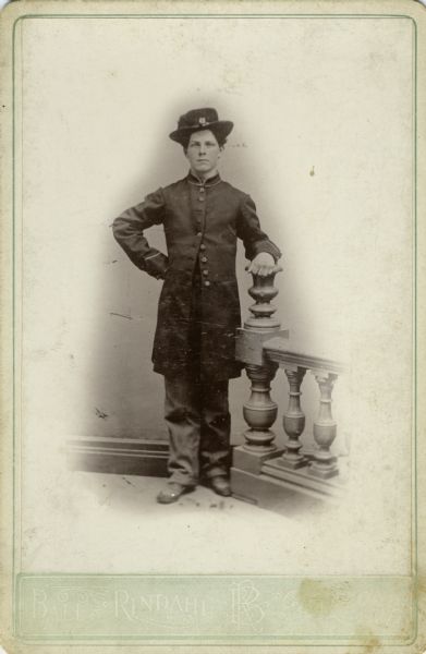 Full-length cabinet card portrait of Syvert A. Lee, a private in Company H, 15th Wisconsin Infantry in uniform next to a prop baluster and railing. The following information was obtained from the Regimental and descriptive Rolls, Volume 20: He resided in Deerfield, Wisconsin. On January 25, 1864, he enlisted into service and on February 16, 1864, he mustered into service and the age of 19. He joined up with Company H on March 31, 1864, at Strawberry Plains, Tennessee.  On May 27, 1864, during the fighting at Altoona Mountain, near New Hope Church, Georgia, he was taken prisoner and listed as missing in action. On February 13, 1864, he was temporarily attached to the 24th Wisconsin Infantry and was transferred to Company K, Wisconsin 13th Infantry on June 13, 1865. He was mustered out of service with Company K, Wisconsin 13th Infantry on November 11, 1865, at San Antonio, Texas.