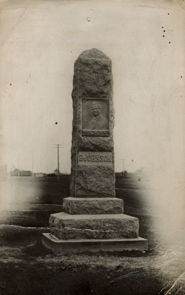 Stone monolith with a bronze relief of Bjørnstjerne Bjørnson. His last name is carved below his portrait.