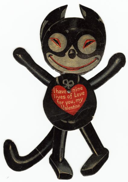 Valentine's Day card of a black cartoon cat made of five pieces. It has a metal paper fastener in the center that allows movement of the head, legs and tail. There is a red heart on its chest with the text: "I have nine lives of Love for you, my Valentine." Offset lithography and die cut in Germany.
