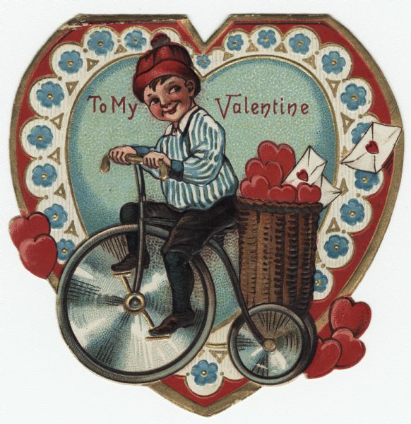 Valentine's Day card with a boy on a trike. He has a basket of hearts and letters on the back, and is wearing a red hat, blue and white striped shirt and black knee pants, stockings and shoes. The background is a heart decorated with blue Forget Me Not flowers and hearts. The text at the top reads: "To My Valentine." Chromolithograph, embossed and die cut. Printed in Germany.