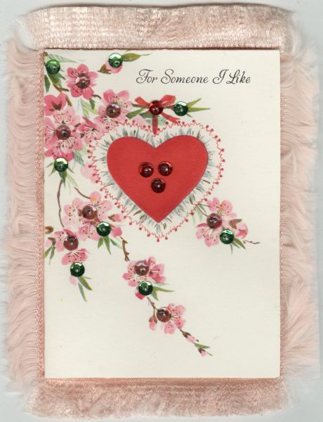Valentine's Day card with a central red heart trimmed with lace. Cherry blossoms surround it. Red, pink and green sequins are sewn onto the card with beads. The text "For Someone I Like" appears at the top. The card was attached to a pink satin sachet with pink fringe, probably by the sender. Offset lithography.