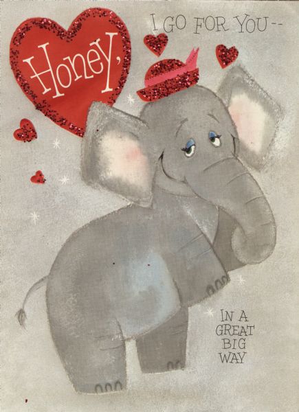 Valentine's Day card with the image of an elephant. She is wearing a red hat with a pink bow and is standing up on her back legs. A red heart in the upper left corner says "Honey," text on the right reads "I Go For You —" and below "In A Great Big Way." Red glitter is glued to her hat and the hearts in the background. The inside (not shown) is a large foldout, die cut face of an elephant with the text "So Let's Be Valentines — OK?" Offset lithography, embossed and die cut with glitter.