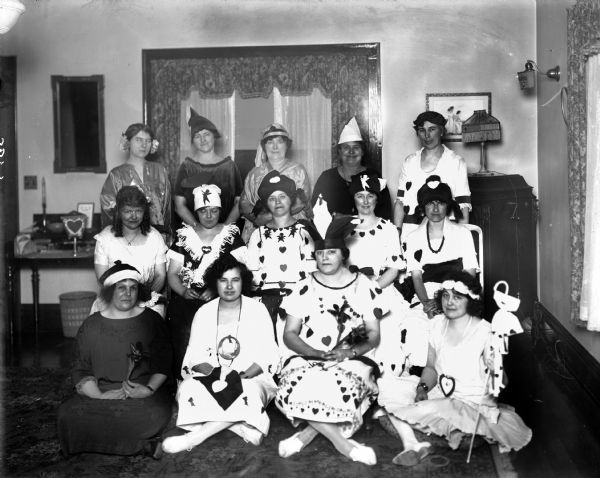 Mrs. D.L. McQuillan and thirteen of her guests at her Valentine's Day party, wearing costumes decorated with hearts, including some elaborate headdresses.
