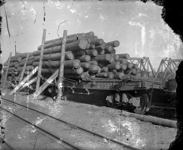 A railroad flatbed car loaded with logs and sitting on railroad tracks.