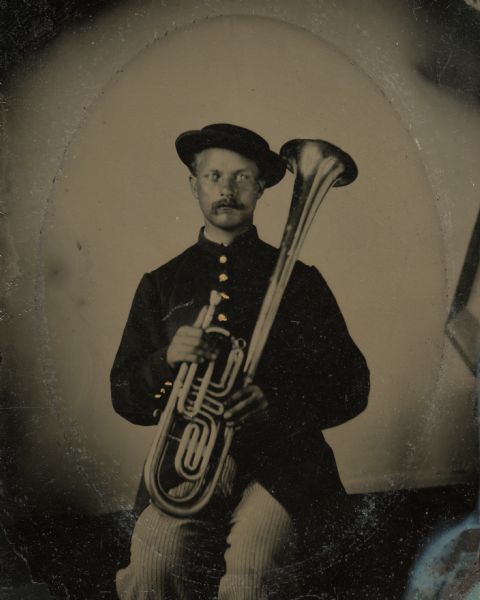 Tintype portrait of Olof Berglund of Darlington, Wisconsin, member of the 3rd Wisconsin Infantry band.  He is seated in uniform and holds a tenor horn. The buttons on his uniform are hand-colored gold.