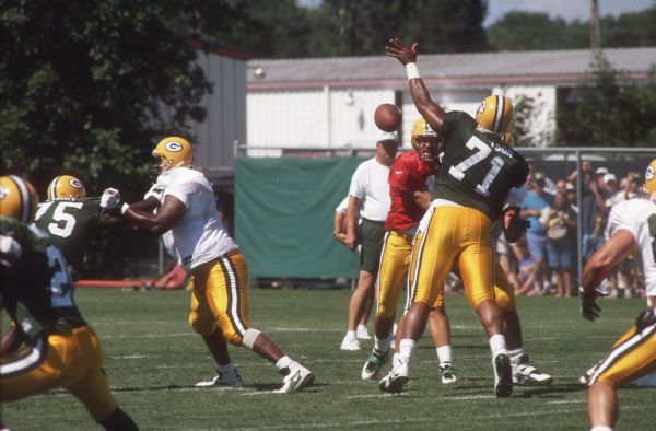 Green Bay Packers quarterback Brett Favre (#4) throwing a pass around defensive back Santana Dotson (#71) at training camp.