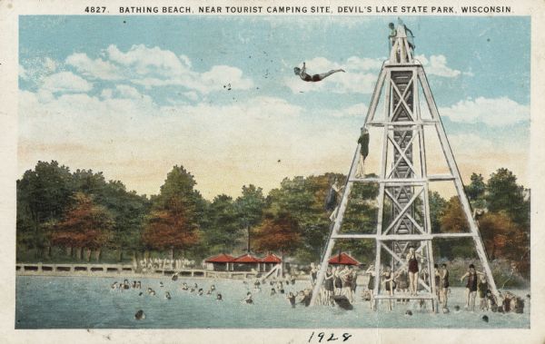 Colorized postcard of the bathing beach near the tourist camping site in Devil's Lake State Park. A diving tower is on the right with a woman diving from the top. Several other people are climbing the tower or waiting their turn, and many swimmers are in the water. Piers and a building are on the shore among trees. The text above reads: "Bathing Beach, Near Tourist Camping Site, Devil's Lake State Park, Wisconsin."