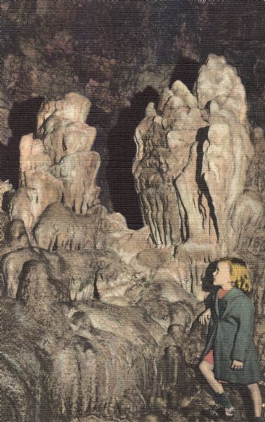 Colorized postcard of Stalagmite Statuary, South Cave, in the Cave of the Mounds. A girl is gazing upwards at the formation.
