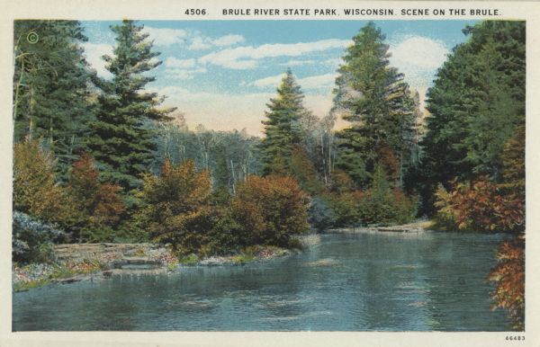 Colorized postcard view of the Brule River flowing through the forest. Some trees show autumn color. Caption reads: "Brule River State Park, Wisconsin. Scene on the Brule."