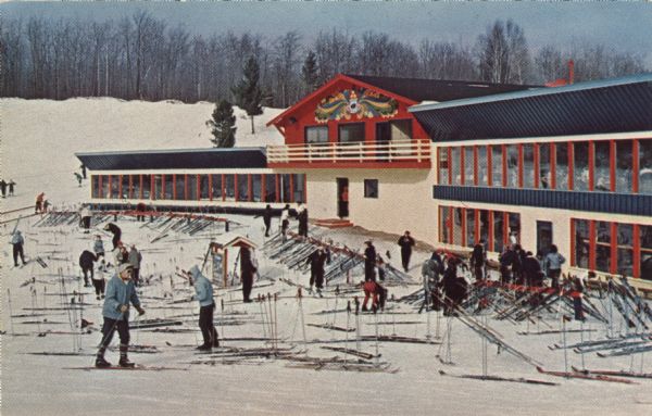 Color postcard of the Chalet at Mt. Telemark. Skiers and skis are in front of the Chalet.