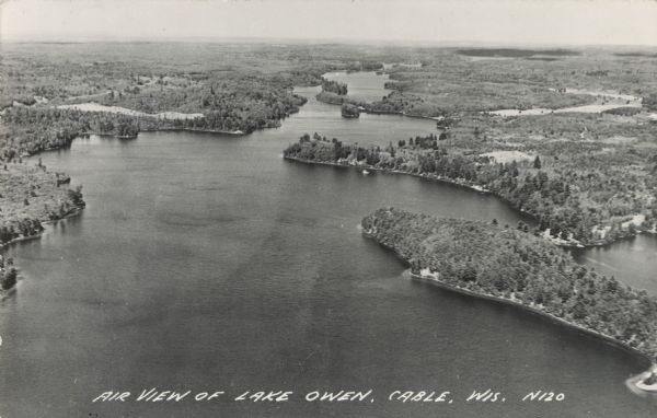 Photographic postcard of an aerial view of Lake Owen near Cable. Most of the lake is located within the Chequamegon National Forest. Caption reads: "Air View of Lake Owen, Cable, Wis."
