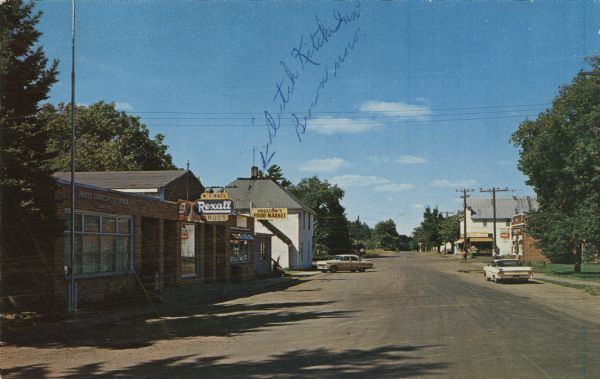 Color postcard of the Main Street Shopping Center, with a food market, a drug store and Post Office.