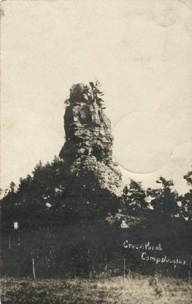 Photographic postcard of Green Point with trees surrounding the base. Handwritten in the lower right corner: "Green Point, Camp Douglas, Wis."