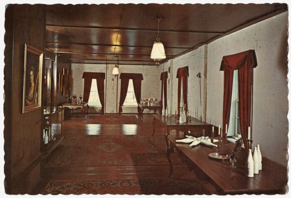Color photographic postcard view of the Von Stiehl Wine Salon at the Von Stiehl Winery. Interior view of the Wine Salon. Wine bottles and candelabras are displayed on four tables lining the walls of the salon. Red curtains and carpets decorate the room.