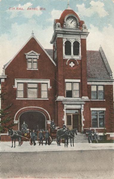 Colorized view of the old three-story, red brick city hall and firehouse. View of the building's exterior includes a team of horse-drawn fire wagons and fire fighters. Caption reads: "City Hall, Antigo, Wis."