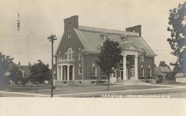 Photographic postcard view of the exterior of the old Carnegie Library on Superior Street. Caption reads: "Carnegie Library, Antigo, Wis."