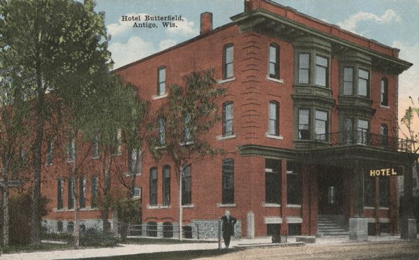Color view of the Hotel Butterfield. A man is standing on the sidewalk, leaning against a pole. Caption reads: "Hotel Butterfield, Antigo, Wis."