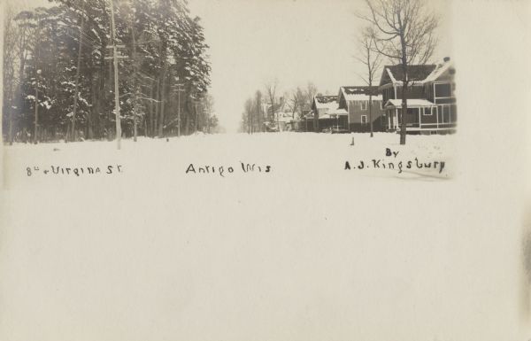 Photographic postcard view of the snow-covered neighborhood at the intersection of 8th and Virginia Street. Caption reads: "8th and Virginia St., Antigo, Wis."