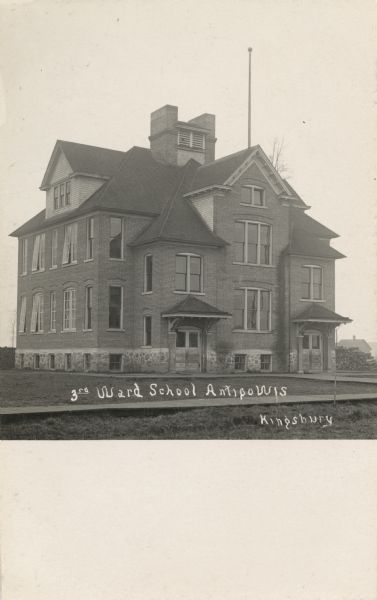 Exterior view of the school, a brick three-story building surrounded by a lawn, and with board sidewalks. Caption reads: "3rd Ward School, Antigo, Wis."