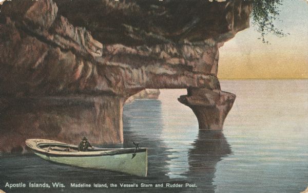 Postcard of the "Vessel's Stern and Rudder Post" geological formation on Madeline Island, one of the Apostle Islands. View of the shoreline and a man sitting in a boat in the foreground. Caption reads: "Apostle Islands, Wis. Madeline Island, the Vessel's Stern and Rudder Post."