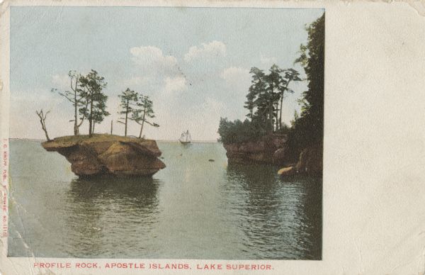 Colorized postcard of the Profile Rock geological formation among the Apostle Islands on Lake Superior. A sailboat is in the far background Caption reads: "Profile Rock, Apostle Islands, Lake Superior."