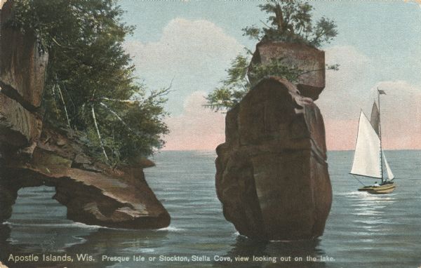 Colorized postcard of Stella Cove looking out on the lake near Presque Isle or Stockton Island, part of the Apostle Islands. A sailboat is on the right. Caption reads: "Apostle Islands, Wis. Presque Isle or Stockton, view looking out on the lake."